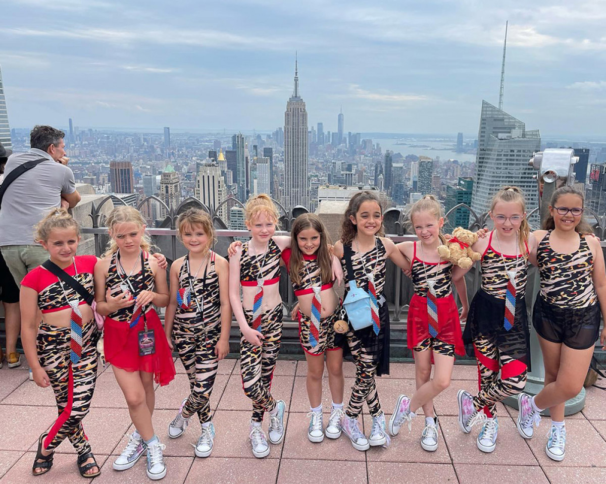 Dance troupe smiling above the New York skyline